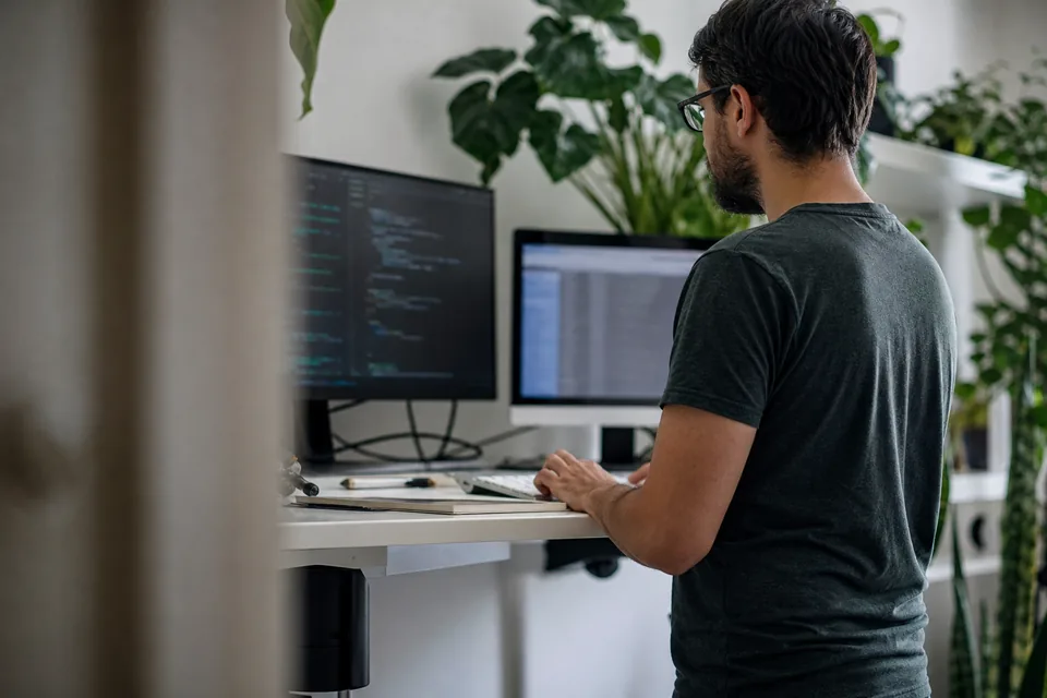 Developer at a standing desk with a terminal and a data table on screen