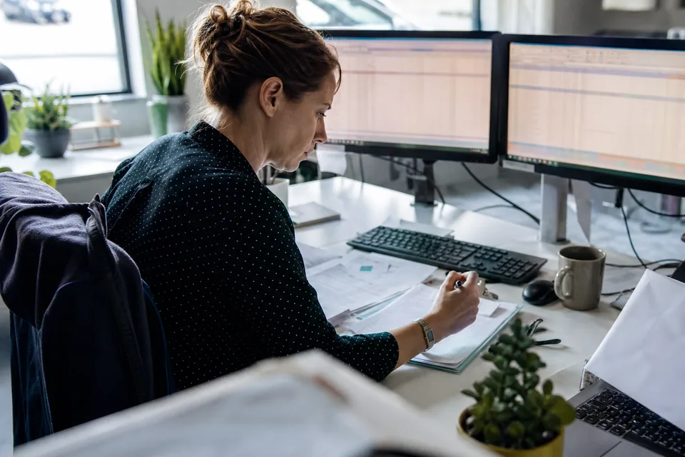 Operations analyst working with spreadsheet grids on two monitors