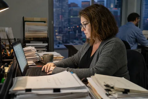 Accounts payable specialist reviewing incoming email attachments in the evening