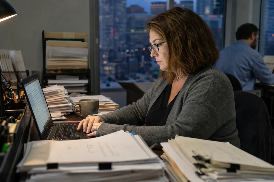 Accounts payable specialist reviewing incoming email attachments in the evening