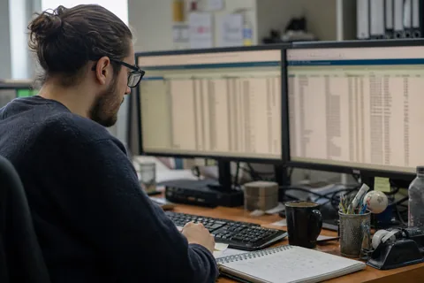 Database administrator checking query results on two monitors