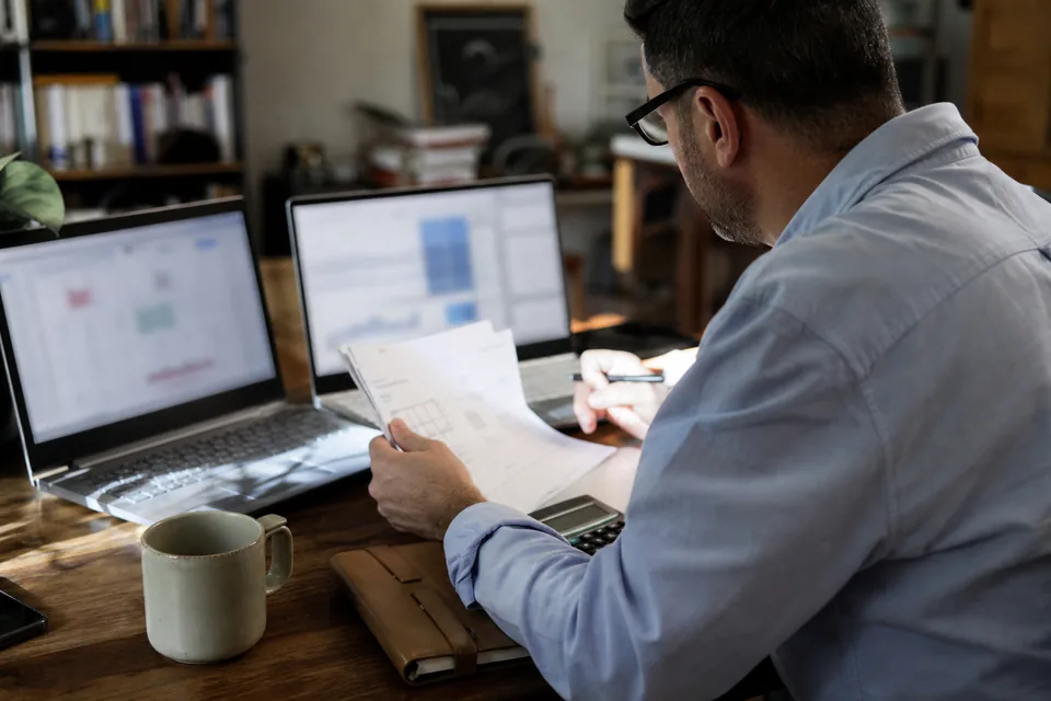 Operations manager comparing two file conversion services on two laptops